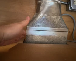 Range hood duct transition inside a cabinet, disconnected at the hood and patched with tape