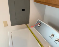 Washing machine parked in front of an electrical panel, blocking the required working space