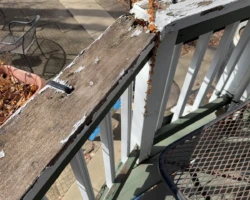 Deteriorated wooden porch guardrail with loose posts and weathered balusters