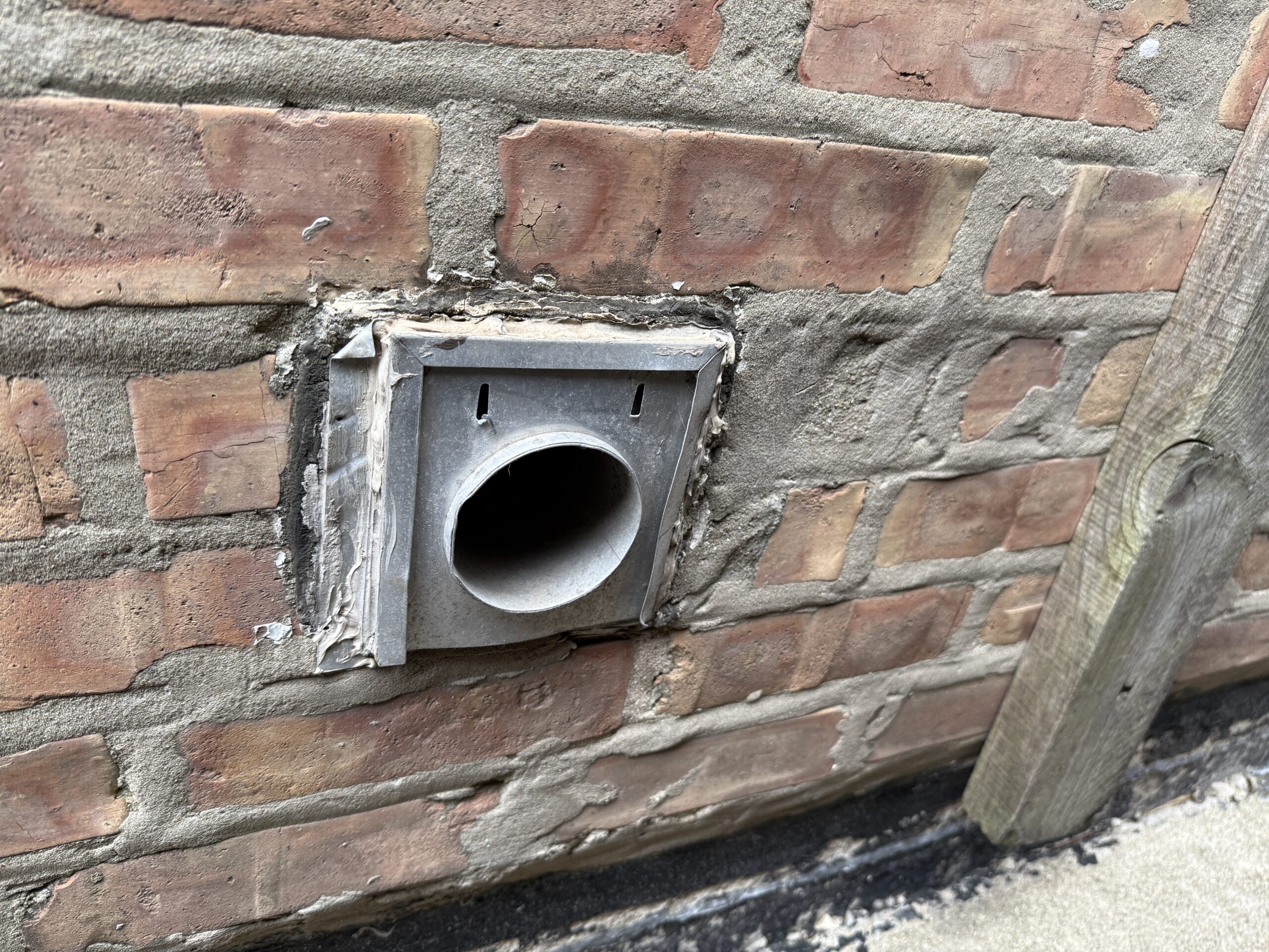 Dryer vent terminating through an exterior wall with no vent cap or damper fitted