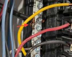 Stranded copper conductors at a breaker terminal with loose frayed strands standing out
