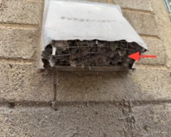 Exterior dryer vent hood with a wire screen packed solid with grey lint