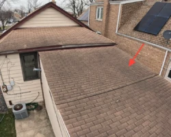 Asphalt shingle roof section at a shallow pitch where shingles are not rated to perform