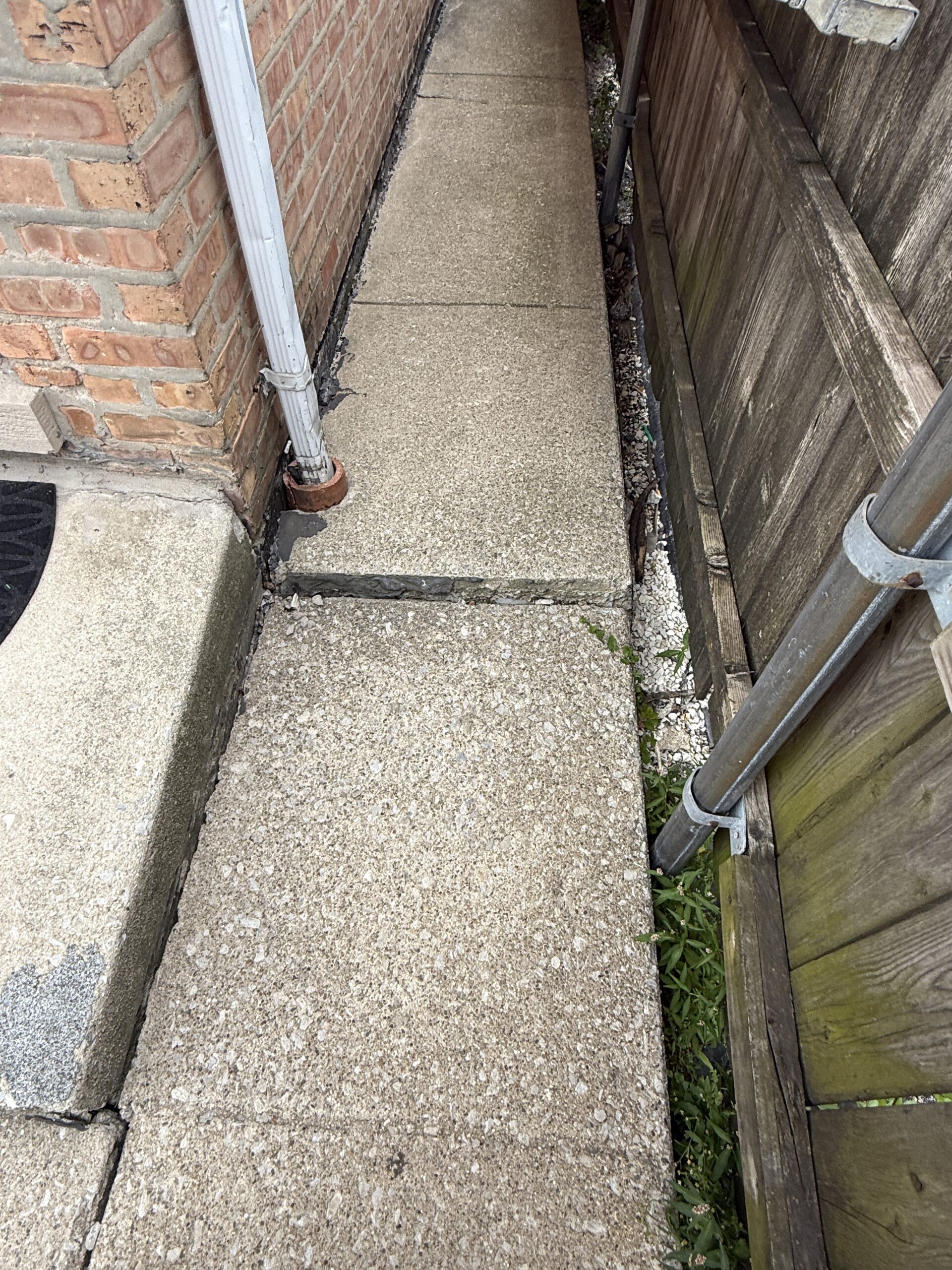 Concrete walkway slabs displaced at a joint, creating a raised trip hazard