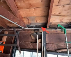 Worn garage roof shingles with widespread granule loss exposing the asphalt mat