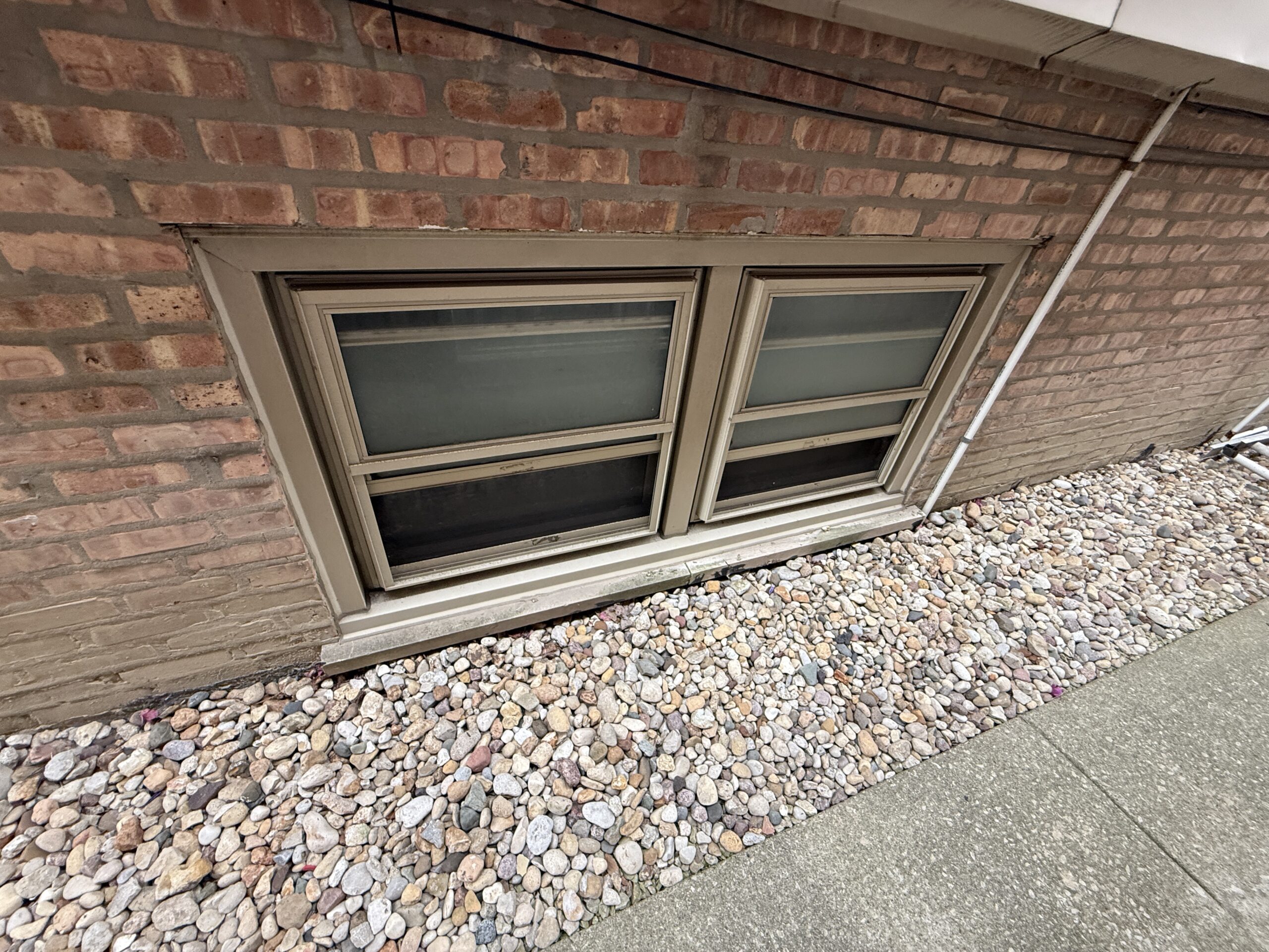 Basement window set nearly level with the surrounding soil, with no clearance above grade