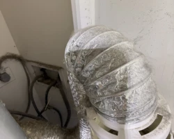 Clothes dryer exhaust hose discharging into a lint collection bucket inside the laundry area