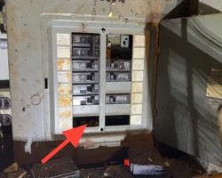 Electrical panel front with open circular knockouts and gaps exposing the interior