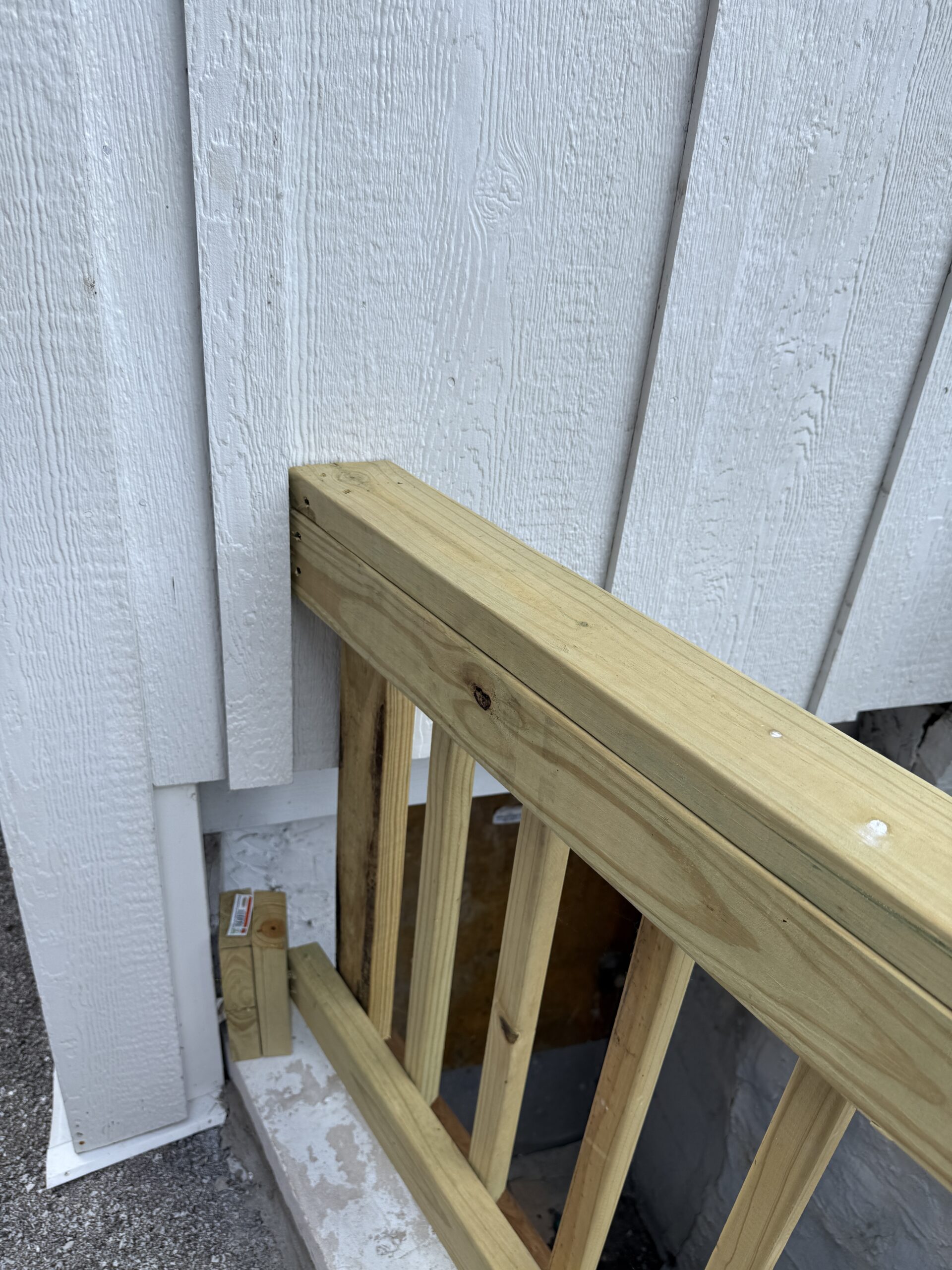Deck guardrail post toe-nailed into exterior siding rather than bolted to structural framing